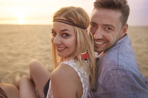 Mooie paar zittend op het zandstrand — Stockfoto