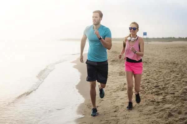 Casal correndo juntos na praia — Fotografia de Stock