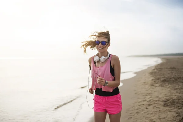 Vrouw joggen op het strand in de ochtend — Stockfoto