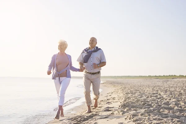 Senior couple running on the beach — Stock Photo, Image