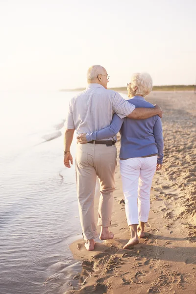 Seniorenpaar geht am Strand spazieren — Stockfoto