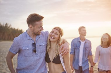 Sahilde günbatımı sırasında çiftler