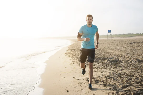 Handsome man running on the beach — Stock Photo, Image