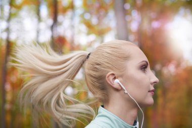 Kadın koşuyor ve müzik dinliyor.