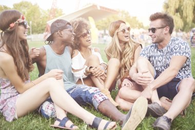 Yeşil çimenlerin üzerinde oturan arkadaşlar  