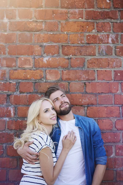 Pareja soñadora de pie junto a la pared de ladrillo — Foto de Stock