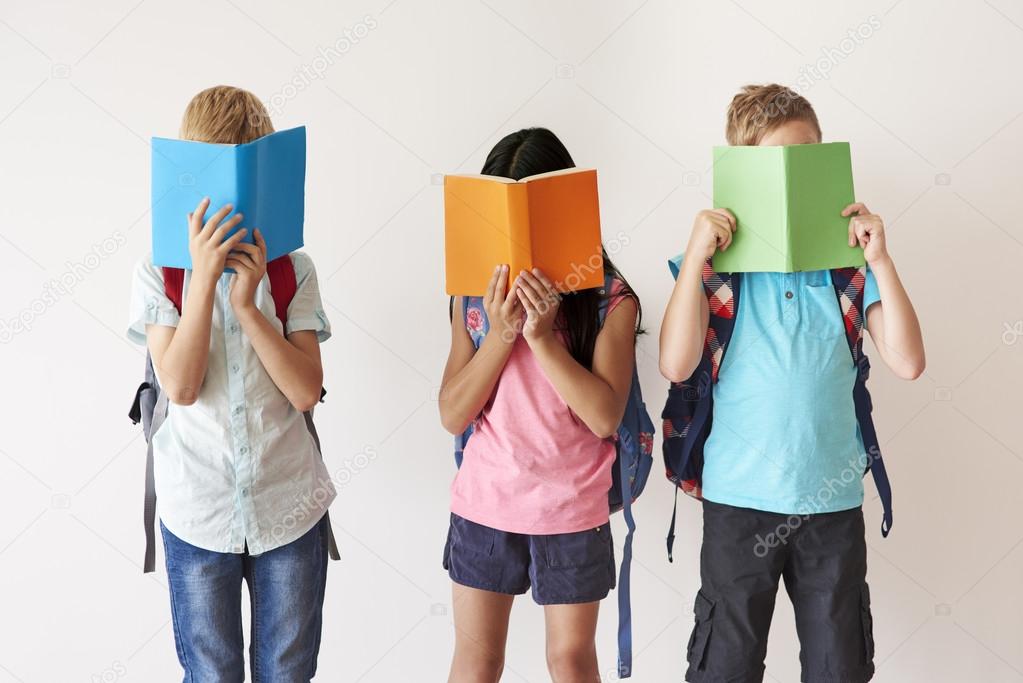 Children covering their faces with books 