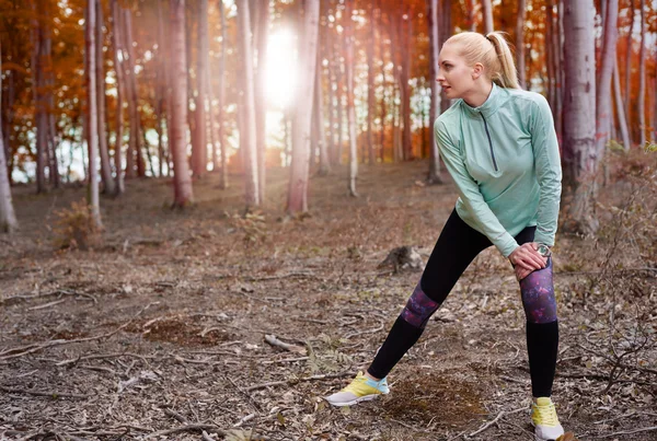 Woman stretching legs in forest — Stock Photo, Image