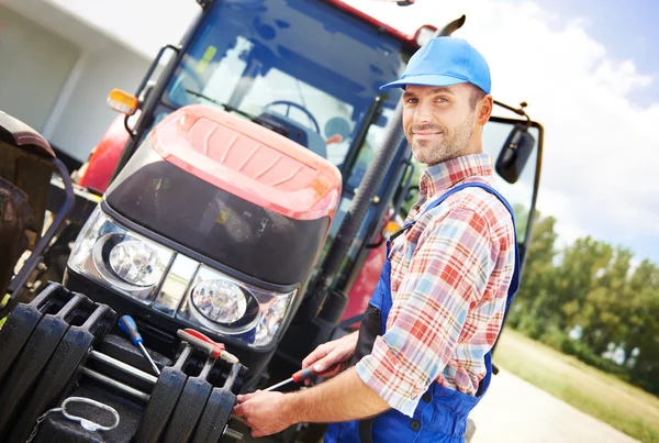 Agricultor reparando su gran tractor — Foto de Stock