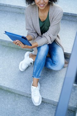 Şehrin merdivenlerinde tabletle oturan üst düzey kadın.                               