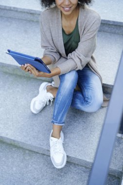 Şehrin merdivenlerinde tabletle oturan üst düzey kadın.                               