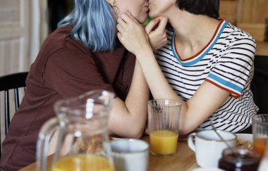 Kahvaltı sırasında öpüşen tanınmayan lezbiyen çift.                               