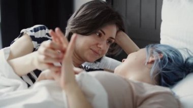 Yatakta el ele tutuşan romantik lezbiyen çiftin videosu. 8K 'da kırmızı helyum kamerayla çekildi..