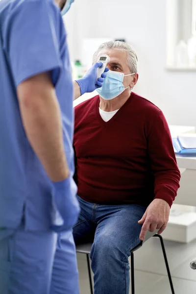 Senior Patient Läkarmottagningen Medan Tar Temperaturmätning — Stockfoto