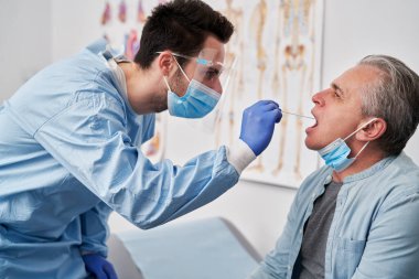 Doktor koronavirüs testi için örnek alıyor.                               