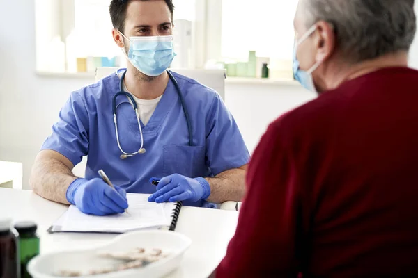 Läkare Skyddande Ansiktsmask Pratar Med Äldre Patient — Stockfoto