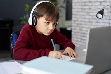 Evde ders çalışırken konsantre olan çocuk.                               