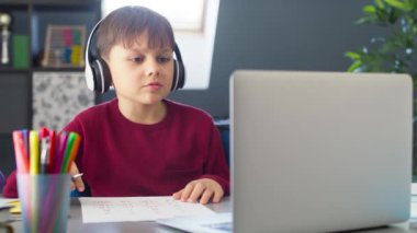 Evde uzaktan öğrenme sırasında kulaklıklı bir çocuğun el kamerasıyla çekilmiş videosu. 8K 'da kırmızı helyum kamerayla çekildi..