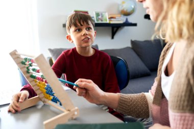 Anne abaküs kullanmayı öğretirken çocuk merak ediyor.                               