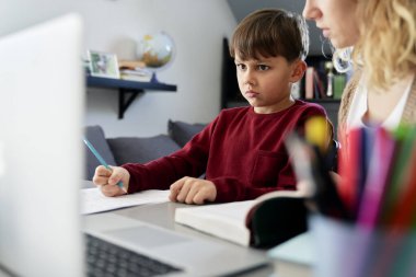 Tatminsiz çocuk annesiyle ödev yapıyor.