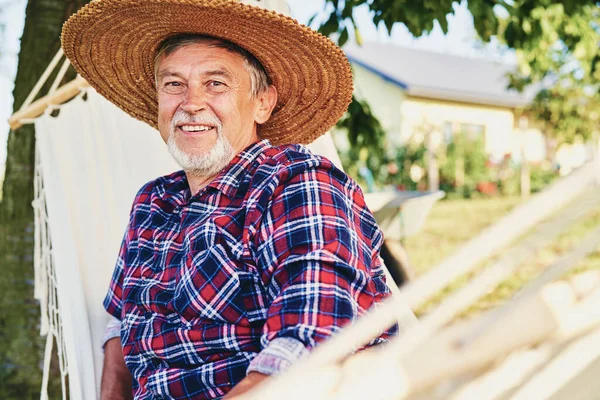 Portrait of senior man in a hat relaxing in a hammock