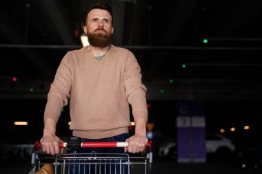 Alışveriş yaptıktan sonra boş otoparkta yürüyen adam                               