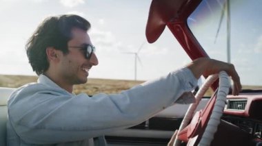 Kırmızı bir araba süren mutlu bir adamın yan görüntüsü. 8K 'da kırmızı helyum kamerayla çekildi..