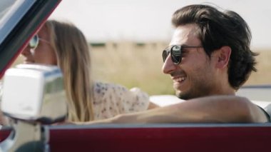 Kırmızı bir Cabriolet kullanan bir çiftin yan görüntüsü. 8K 'da kırmızı helyum kamerayla çekildi..