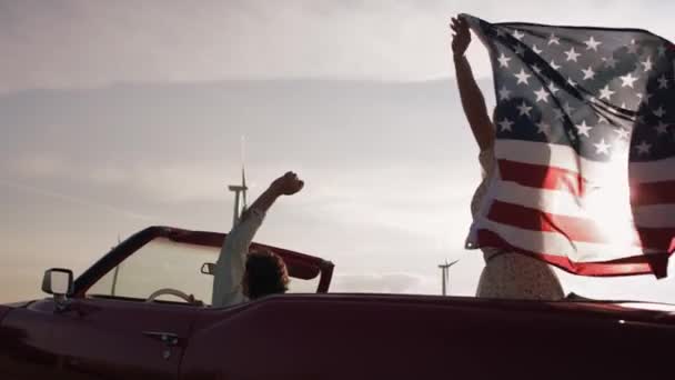 Vídeo Casal Carro Com Uma Bandeira Americana Tiro Com Câmera — Vídeo de Stock