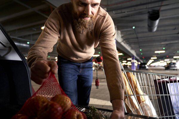 Man packing shopping bags in a car trunk                               