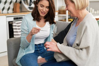 Evde annesinin yanında hamilelik testi olan mutlu bir kadın.