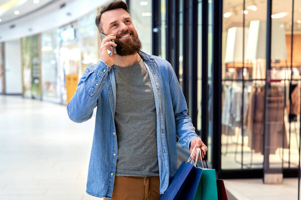 Happy man calling while shopping at the mall                               