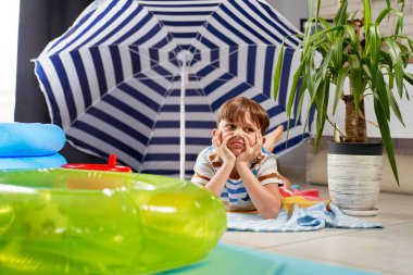 Sıkıcı çocuk sahildeki tatilini evde geçiriyor.                               