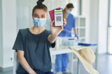 Elinde dijital aşı kartı olan bir kadın.                               