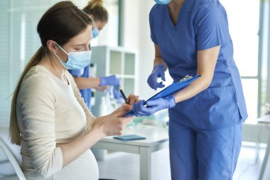 Hamile kadın aşılanmadan önce belgeleri imzalıyor                               