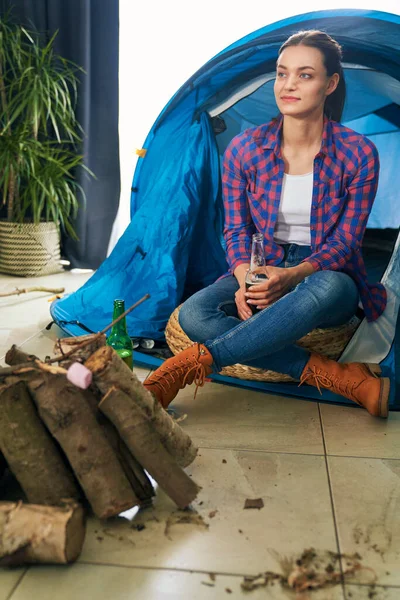 一个女人坐在家里露营时喝啤酒 — 图库照片