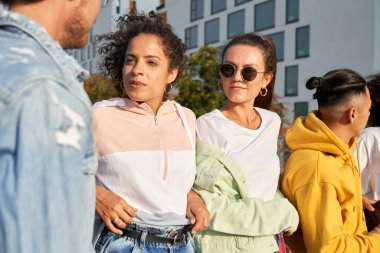 Gün batımında ayakta duran ve konuşan bir grup genç arkadaş.                               