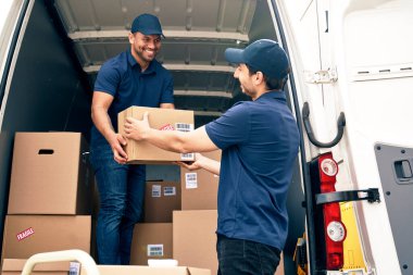 Arabadan paketleri boşaltan iki mutlu kurye.                               