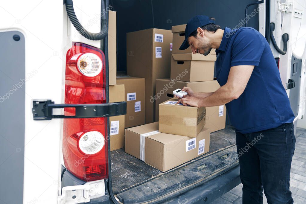 Smiling courier checking packages using portable information device