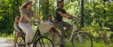 Ormanda bisiklete binen eğlenceli aile videosu. 8K 'da kırmızı helyum kamerayla çekildi..