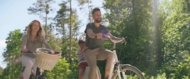 Ormanda bisiklete binen eğlenceli aile manzarası. 8K 'da kırmızı helyum kamerayla çekildi..