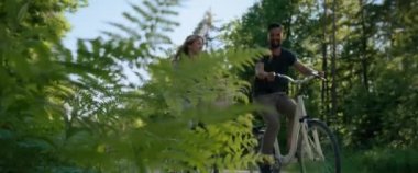 Ormanda bisiklete binen mutlu çiftin alt manzarası. 8K 'da kırmızı helyum kamerayla çekildi..