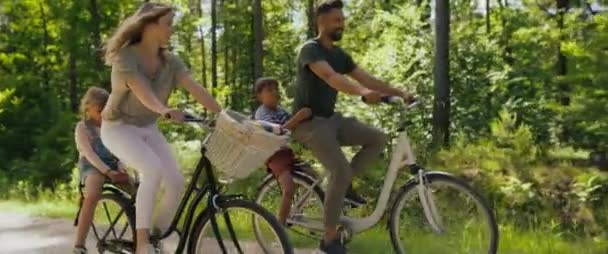 森の中で遊び心のある家族の乗馬バイクのビデオ 8Kでレッドヘリウムカメラで撮影 — ストック動画
