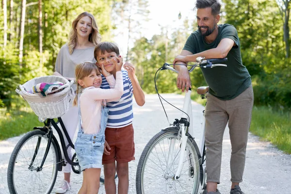 带着顽皮孩子的家庭骑自行车在森林里 — 图库照片
