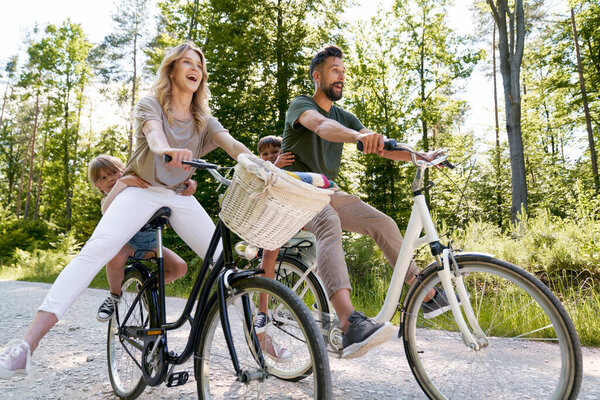 Exuberant family riding bicycles in the forest                               