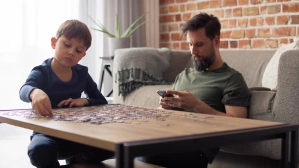 Video Boy Solving Jigsaw Puzzle Father Using Phone Shot Red — Stock Video
