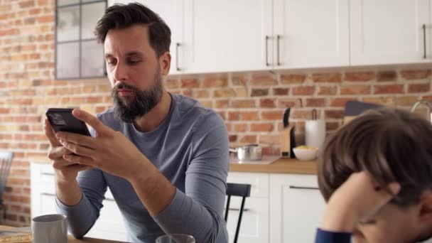 Video Del Padre Hijo Usando Teléfono Móvil Mientras Desayunan Fotografía — Vídeos de Stock