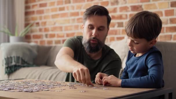 父親とジグソーパズルを解く少年のハンドヘルドビデオ 8Kでレッドヘリウムカメラで撮影 — ストック動画