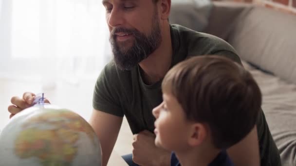 儿子和父亲看着旋转的地球仪的手持视频 用8K的红色氦相机拍摄 — 图库视频影像