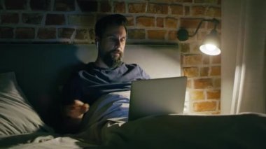 Video konferans sırasında yatakta yatan adamın videosu. 8K 'da kırmızı helyum kamerayla çekildi..